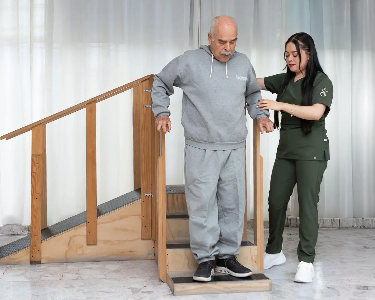Fisioterapeuta acompañando a paciente adulto mayor en rehabilitación con escaleras en Balance Texcoco